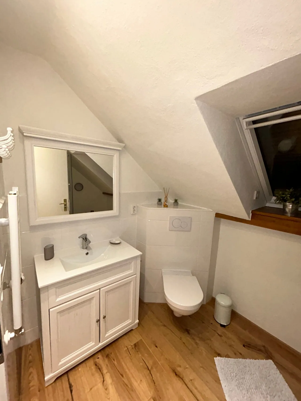 Ferienwohnung III: Badezimmer mit Waschtisch, Spiegel und WC unter der Dachschräge