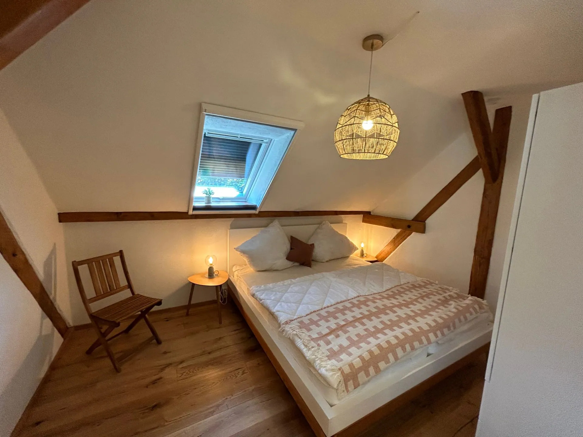 Ferienwohnung III: Schlafzimmer mit Doppelbett unter der Dachschräge und Dachfenster über dem Bett
