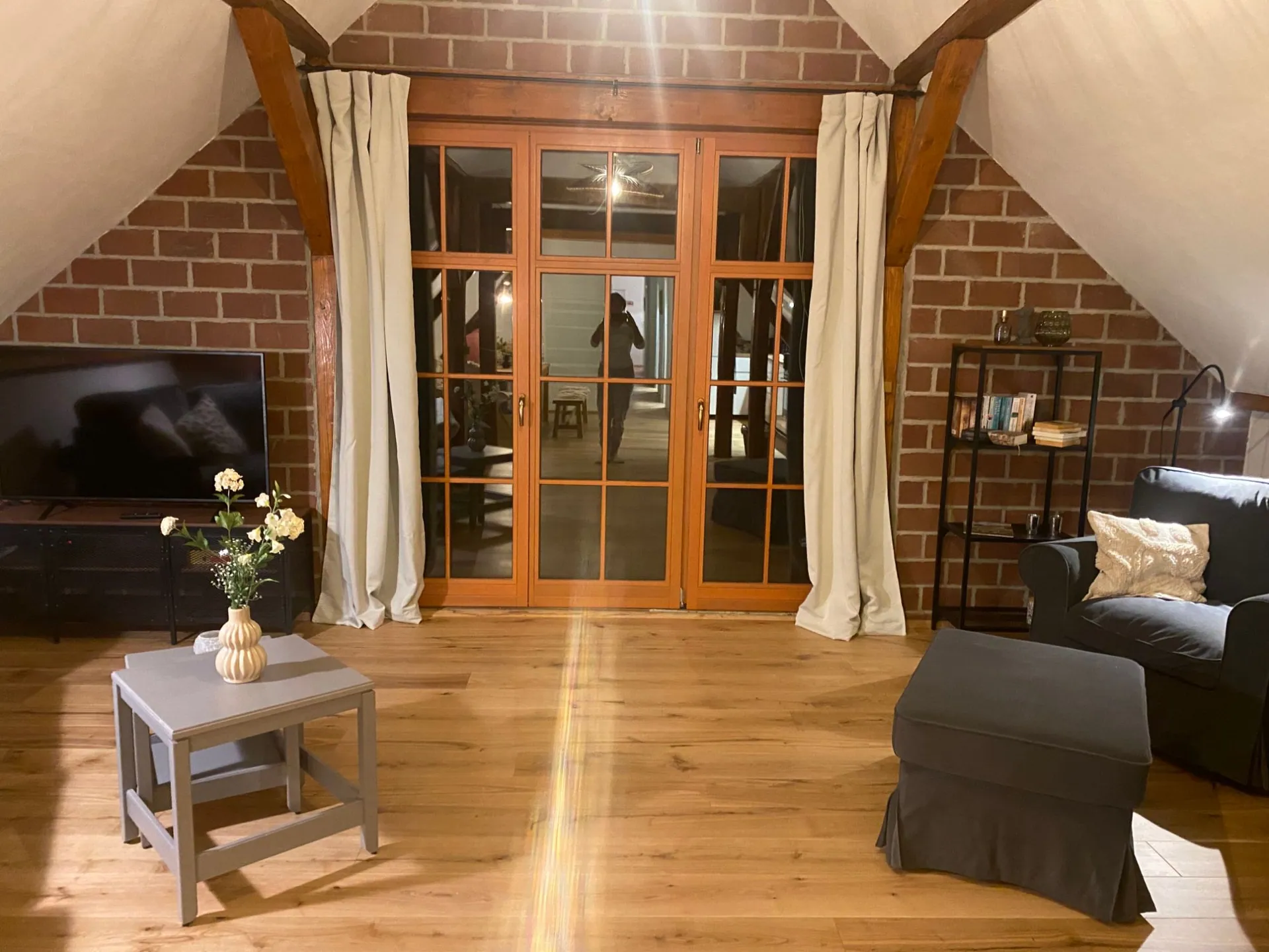 Ferienwohnung III: Wohnstube am Abend mit Backsteingiebel, Flügeltür zum Flur und Sitzecke